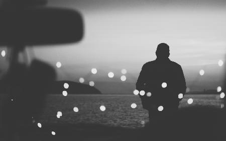 Silhouette eines Reisenden auf dem Hintergrund des Wassers am Abend