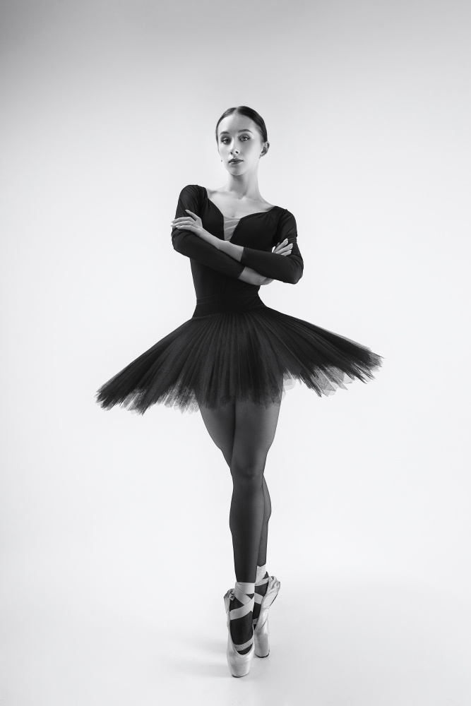schwarzer Schwan. Ballerina im schwarzen Tutu zeigt Elemente des Balletttanzes in Bewegung von Alexandr