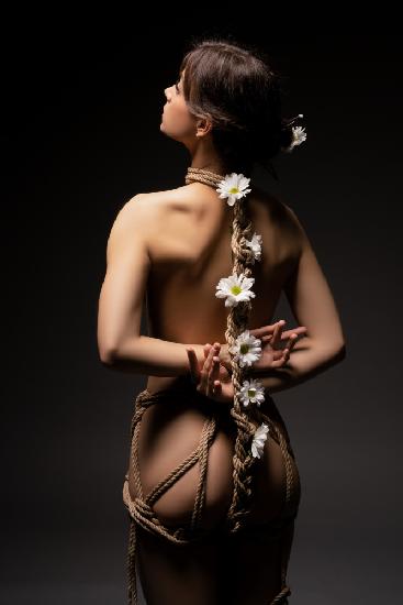Frau mit Seilen und Blumen gefesselt