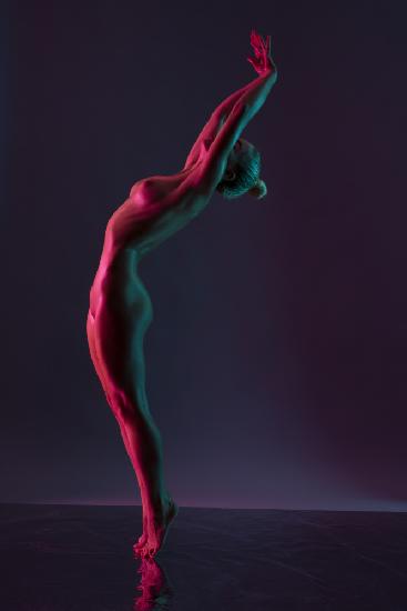 Junge nackte Frau tanzt vor dunkelviolettem Hintergrund