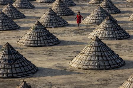 Kinder laufen zwischen Hunderten traditioneller Reismühlen aus Bambus umher