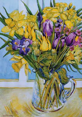 Daffodils and tulips in a glass jug by a window