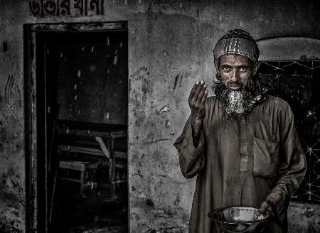 Ein Mann aus Bangladesch grüßt an einem regnerischen Tag
