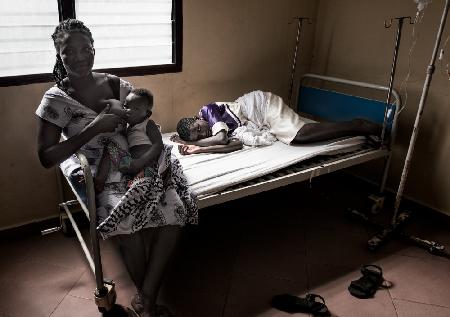 Eine Großmutter stillt ihren Enkel,während sie ihre kranke Tochter besucht – Ghana