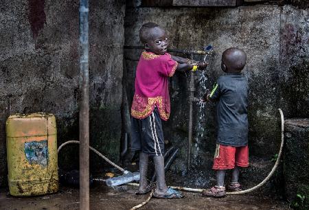 Kinder des Surmi-Stammes reinigen ihre Hände,bevor sie mit dem Essen beginnen – Äthiopien