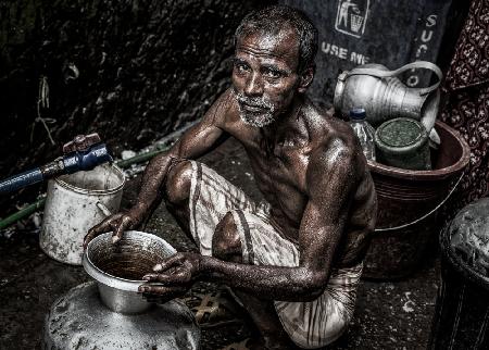 Mann füllt einen Krug mit Wasser in den Straßen von Bangladesch.