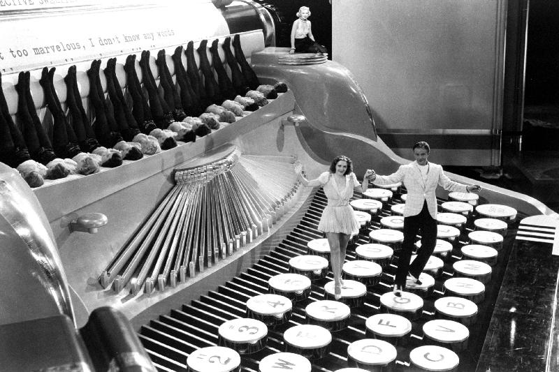 Couple dancing on the key of a giant typewriter, keys are leg of dancers, musical von 