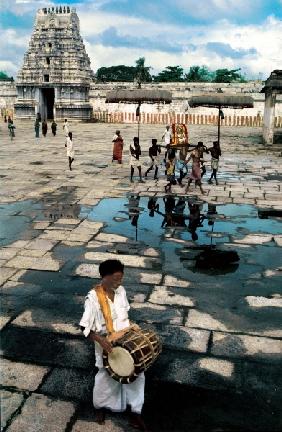 Drummer and devotees reflected in pool of water (photo) 