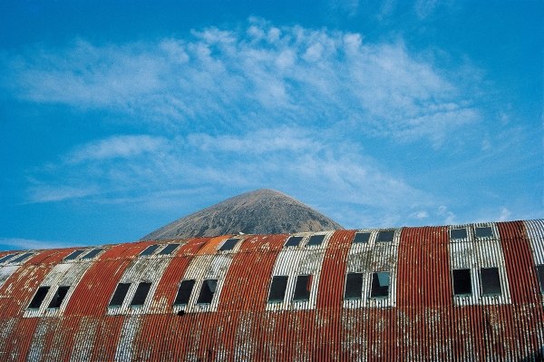 Rusted roof of a deserted warehouse with the breast of a mountain (photo)  von 