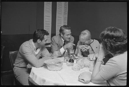 Paul Newman, Mort Sahl and Joanne Woodward joking at dinner 1964
