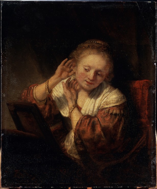 Junge Frau, die Ohrringe anprobiert von Rembrandt van Rijn