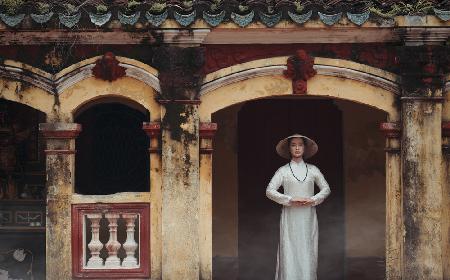 Ein vietnamesisches Mädchen in einem traditionellen Ao-Dai-Kleid betet um Glück